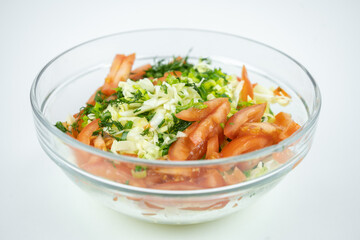 fresh salad with cabbage, tomatoes and greens in a glass bowl