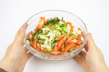 fresh salad with cabbage, tomatoes and greens in a glass bowl