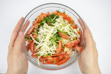 fresh salad with cabbage, tomatoes and greens in a glass bowl