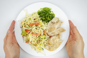 diet dish on a plate with fresh salad with cabbage, tomatoes, greens and chicken breast