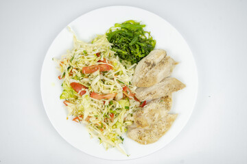 diet dish on a plate with fresh salad with cabbage, tomatoes, greens and chicken breast