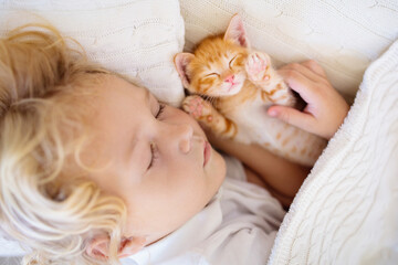 Baby boy sleeping with kitten. Child and cat.
