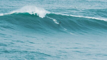 professional surfer rolls on a huge wave on a surf at competitions drone shoots process, slow motion