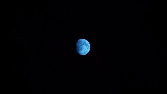 quelques petits nuages fins passent devant la lune bleue &eacute;clair&eacute;e &agrave; 86 % dans un ciel compl&egrave;tement noir