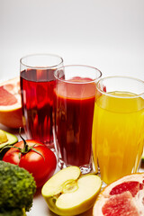juices in glass glasses on a background of fruits on a white background