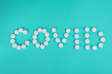 White pills in form word coronavirus on blue background