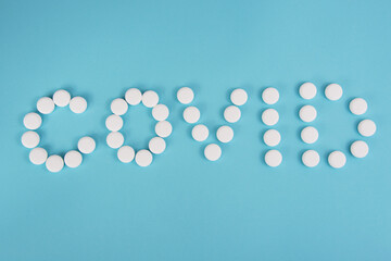 White pills in form word coronavirus on blue background