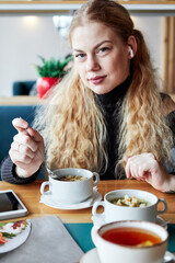 girl with long blond curly hair in a cafe eating soup business lunch
