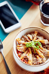 wok noodles with chicken and sesame seeds in a plate on a wooden table with cutlery