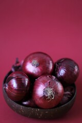 Red onion  close-up on a burgundy background.Fresh farm bio organic vegetables.Food ingredient.Red onion set in a brown cup.