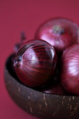 Red onion  close-up on a bright burgundy background.Fresh farm  organic vegetables.Food ingredient.Red onion set in a brown cup.