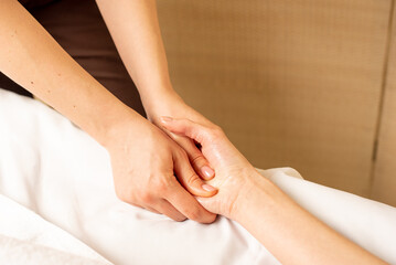 Fototapeta na wymiar Hand massage. Physiotherapist pressing specific spots on female palm. Professional health and wellness acupressure manipulations