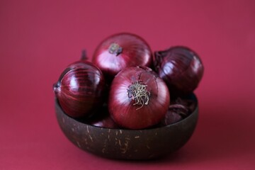 Red onion   on a bright burgundy background.Fresh farm bio organic vegetables.Food ingredient.Red onion set in a brown cup.