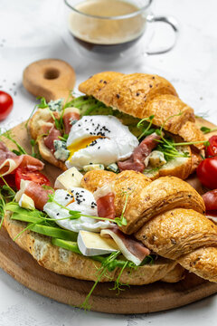 morning poached egg with prosciutto, poached egg, jamon, blue, cheese, avocado, microgin and cherry tomatoes on a light background, Cup of coffee. vertical image