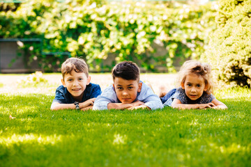 Fototapeta premium Portrait of three little children lying on a green grass