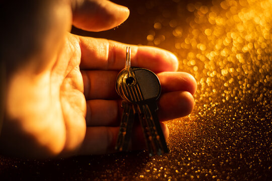 hand holding keys. man taking key to the new home. Male holding keys from new apartment. Light background. Keys concept.