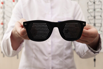 Perforated slit training glasses. An optometrist in an optician's salon invites the client to try...