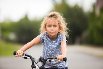 The little girl rides a bike in the city