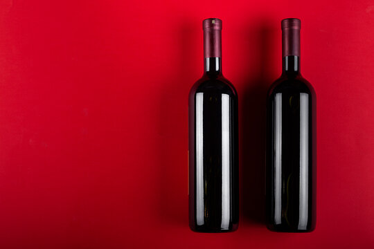 Two bottles of red wine on a red background. Romantic mood. Space for text.
