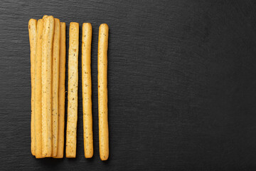 Homemade Italian Grissini Breadsticks on a black background. Traditional italian snack with herbs.  Space for text.