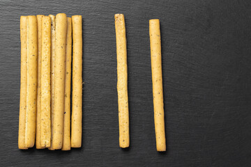 Homemade Italian Grissini Breadsticks on a black background. Traditional italian snack with herbs.  Space for text.
