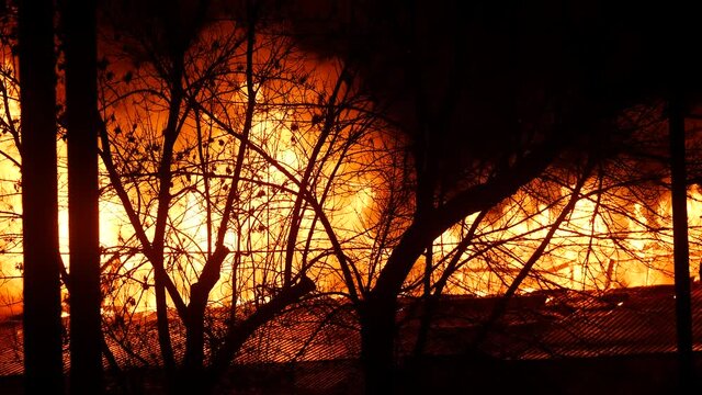 fire on the roof of the house. a burning at night trees building house close-up. home insurance apartment concept. huge fire blazes houses and trees. property damage 911 arson protection