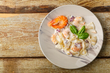 Pasta with shrimps in a creamy sauce, garnished with spinach on a gray plate on a wooden table