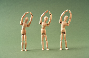 Three wooden figures exercising in a synchronized way