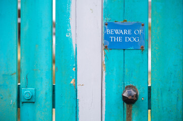 Beware of dog sign on blue wooden house gate