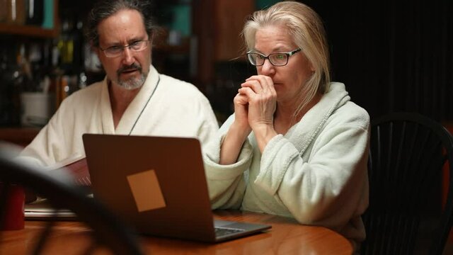 Couple paying taxes at kitchen table in dining room at night and smiling and happy when finding they get a healthy refund and stimulus.