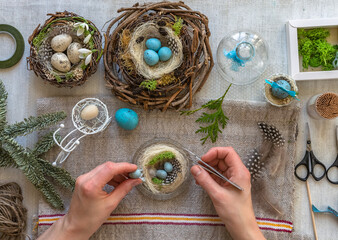 Easter decorations handmade easter crocheted mugs with boxwood in a nest made of rattan on a wooden background on the table with two rattan spheres balls