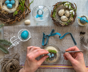 A nest with three white Easter eggs and bunny ears at home on Easter day. Celebrating Easter at spring. Painting eggs.