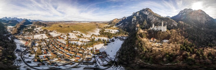 360 Aerial panorama drone shot of picturesque Neuschwanstein Castle on snowy hill in winter sunlight in Germany - obrazy, fototapety, plakaty