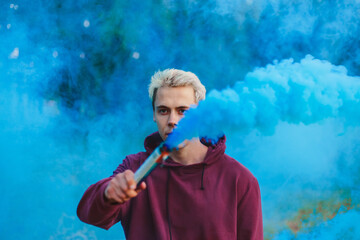 Street style man in hoodie hold hand flare with red smoke grenade bomb. - Powered by Adobe
