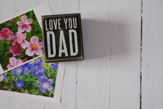 Flowers Photos Beside Fathers Day Plaque on Whitewashed Wood