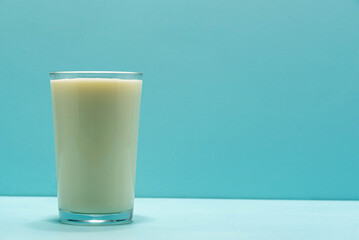 Glass cup with milk on blue background