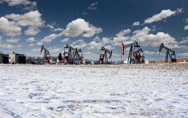 A group of oil pump jacks working on an oil field on the Alberta prairies supplying natural resources for the Canadian oil and gas sector.
