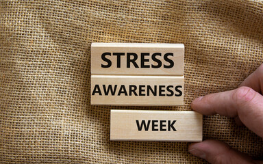 Stress awareness week symbol. Wooden blocks with words 'Stress awareness week'. Beautiful canvas background. Doctor hand. Psychological, business and stress awareness week concept. Copy space.
