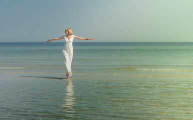 beautiful woman in sunglasses stands and poses in the sea in a white wedding dress