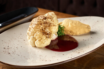 Roasted Cauliflower and Hummus dish with coriander leaf in a wooden table