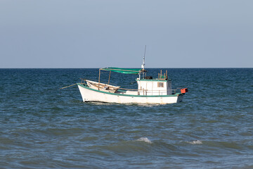Small white fishing boat floating in the ocean - fisherman out to sea to support his family. Yucatan, Mexico