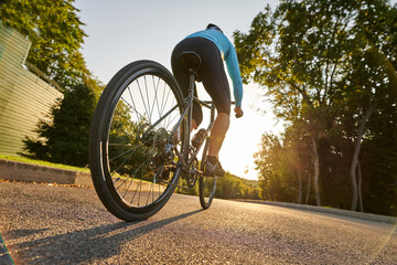 Cycling is for fun. Low angle view of professional male bicycle racer riding his road bike in the...