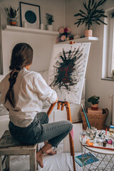 Beautiful talented female artist painting at her home.