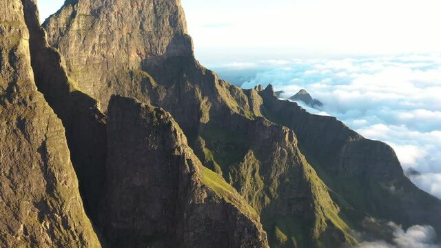 Scenic flight over Drakensberg rocky mountains in morning.   High mountain peaks raising above clouds