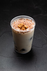Appetizing cream dessert with prunes and walnuts on a dark table