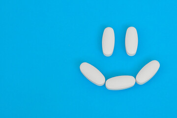 Happy smiling face layd out from white medical pills. Pharmacy, vitamin, tablets.