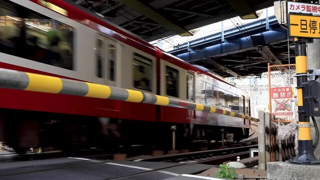 線路のカーブにある小さな踏切を通過する上りと下りの赤い電車
