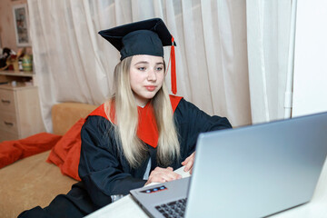 Virtual graduation and convocation ceremony. Excited student wearing graduation gown and cap talking with her family and receiving congratulation during online video call, distant education