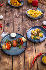 Boiled potatoes, coarse salt, grilled vegetables on a brown wooden background.