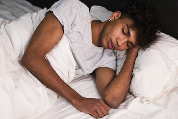 Sleep tight. Portrait of relaxed young guy sleeping in his bed at home